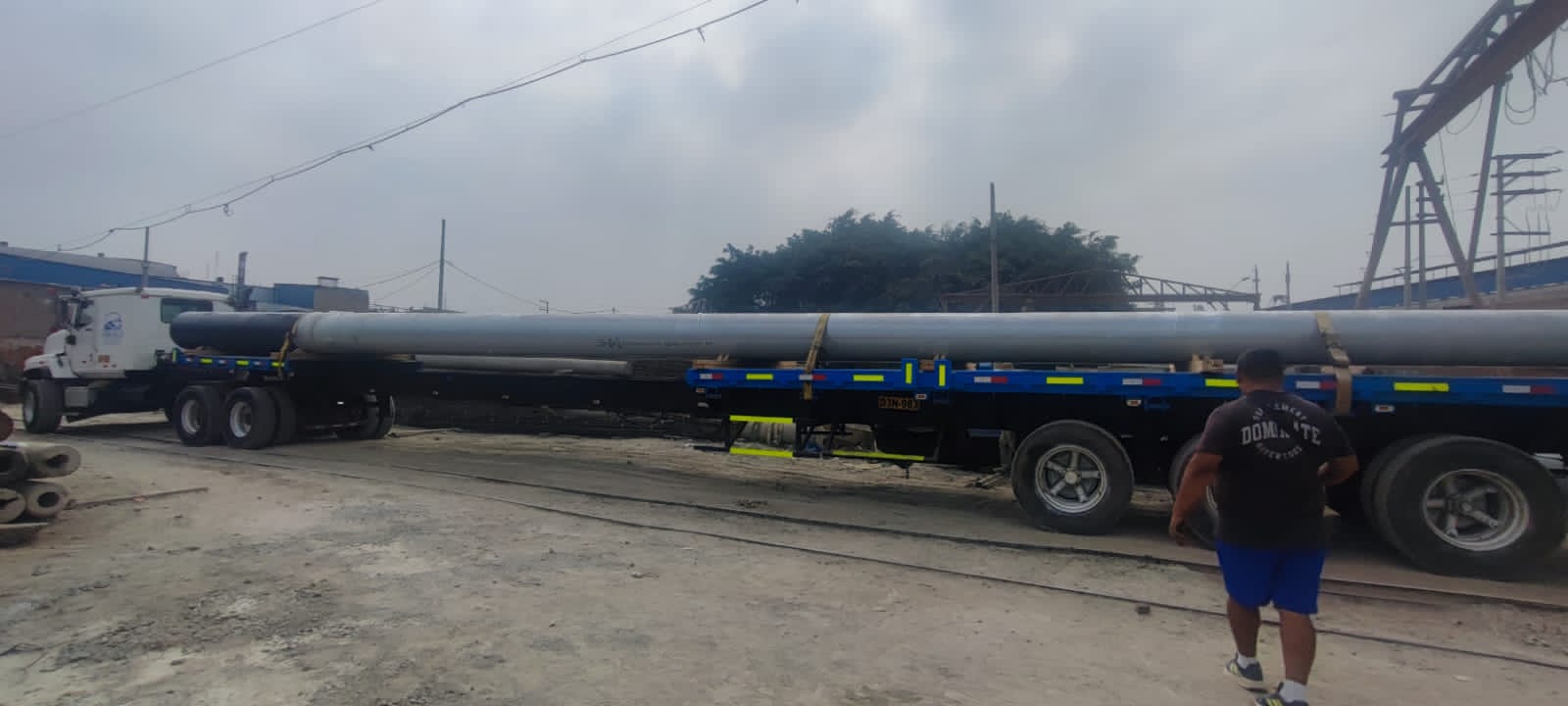 Plataforma cargada con postes de concreto de gran longitud para despacho